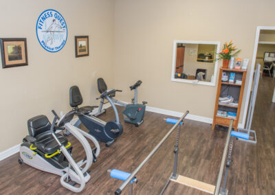 nustep and recumbent bikes in rehab area with parallel bar platform area