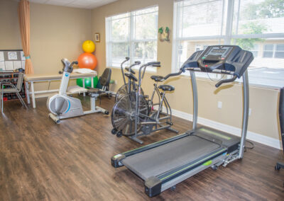 treadmill, stationary bikes and upper body ergometer in treatment area of physical therapy clinic