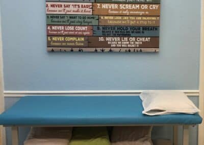 Physical Therapy open treatment area with table and laws of physical therapy poster on wall