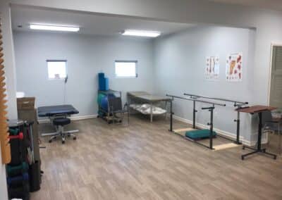 Physical Therapy clinic treatment area with table and balance bars gym area