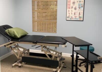 outpatient physical therapy clinic treatment room with table and desk