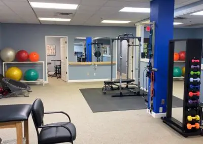 outpatient physical therapy clinic gym area with weights and treatment tables